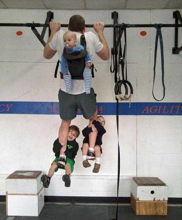 Man doing a Pull-Up with 3 children as additional weight
